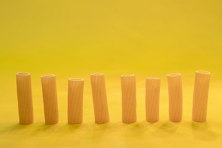 Close-up of wooden chairs against yellow background