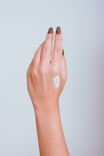 Cropped hand of woman against white background