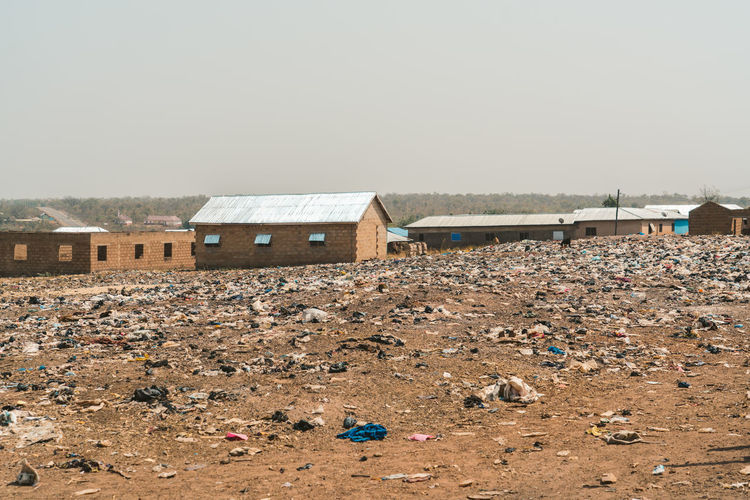 Garbage on field by houses against clear sky