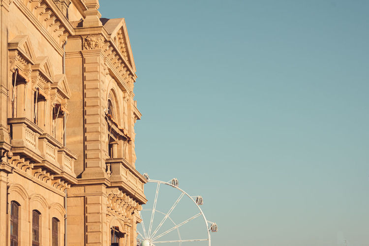 Retro town hall buildings against clear blue sky and ferris wheel