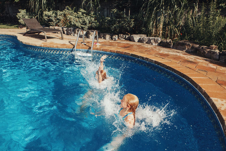 Girls sisters diving in water pool. children friends enjoying and having fun in swimming pool 