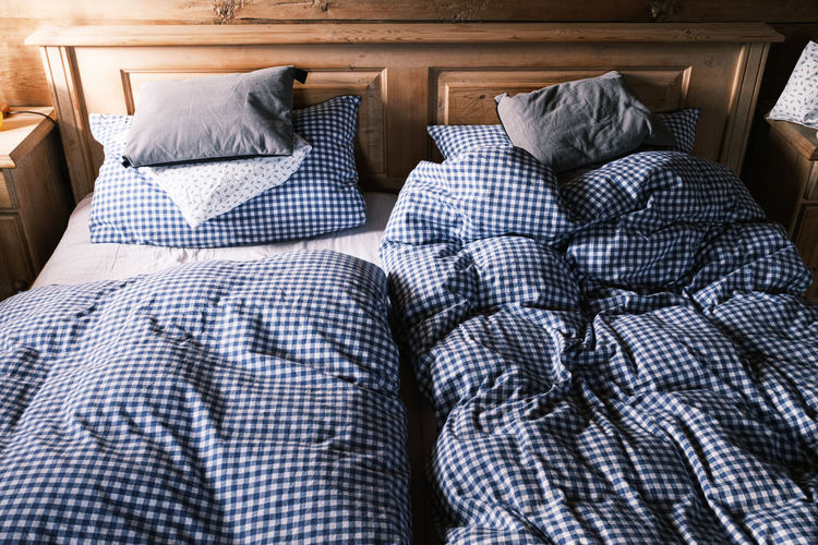 Blue white chequered used bedclothes on wooden bed