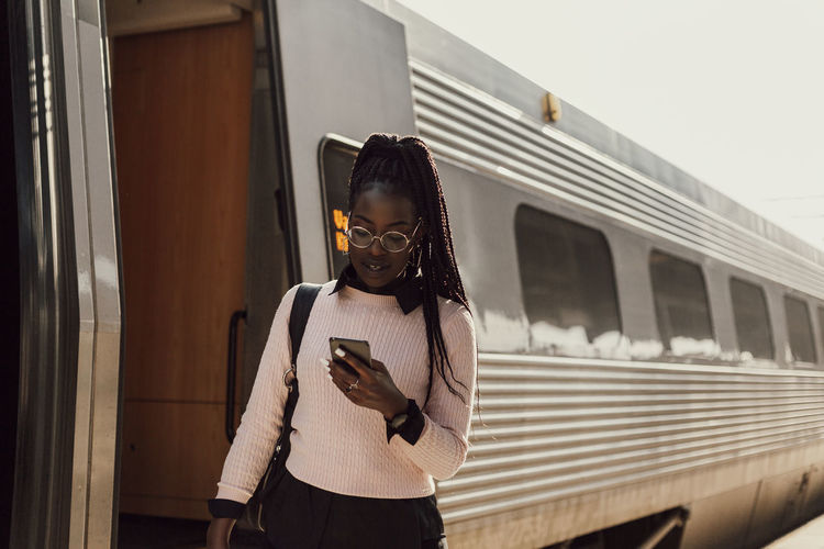 Young woman using phone at train station platform