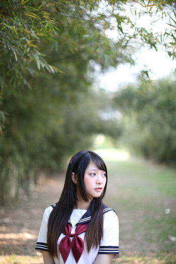 Young woman looking away while standing amidst bamboo groove