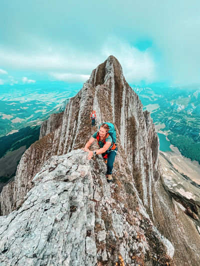 Two female climbers on narrow ridge above alpine lake in swiss alps