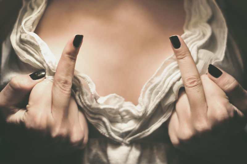 Midsection of woman showing middle fingers