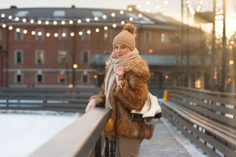 Portrait of woman wearing warm clothing standing by railing in city