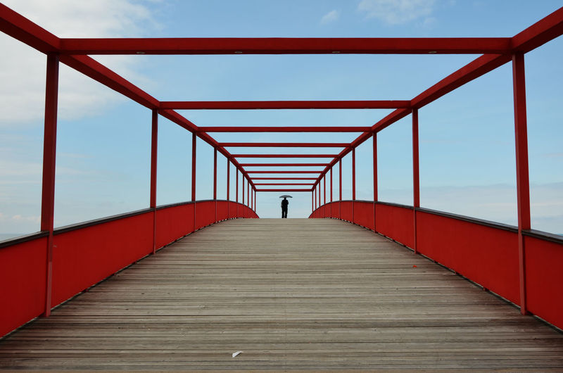 Distant view of person standing on bridge against sky