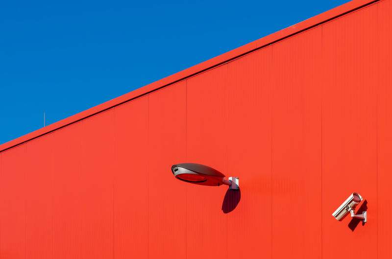 Low angle view of red wall against clear blue sky