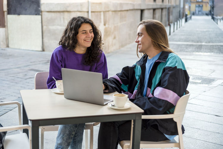 Portrait of young woman using laptop while sitting on table