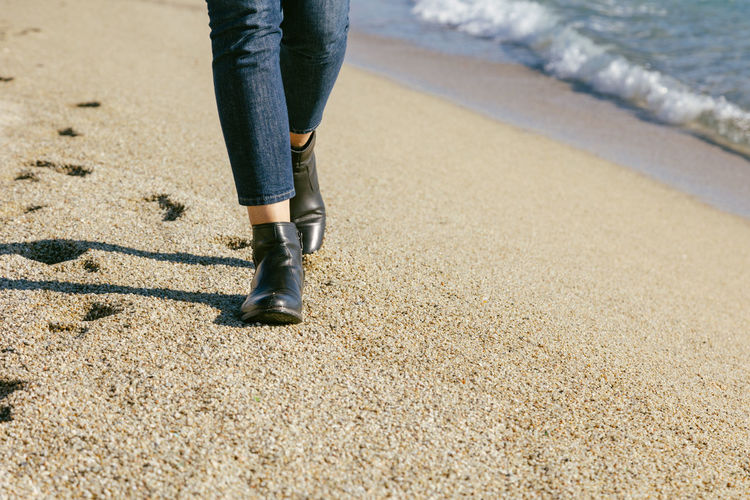 Woman's boots leaving footprints on the beach sand