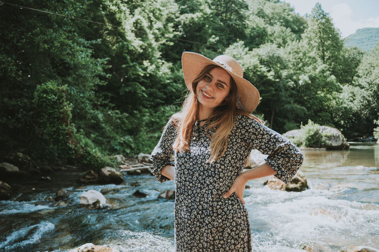 Pretty blonde woman with hat by the river in nature