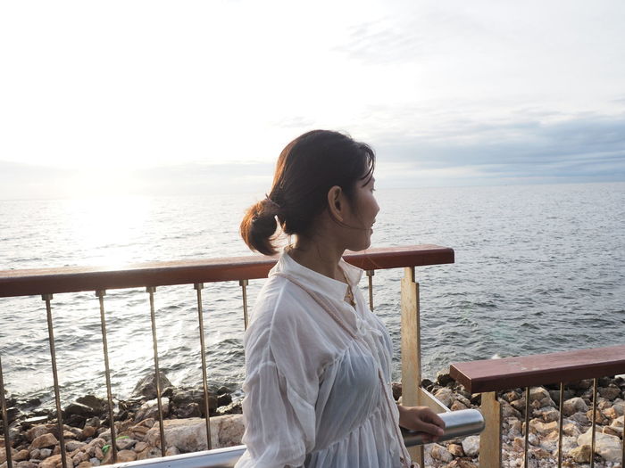 Young woman looking at sea against sky