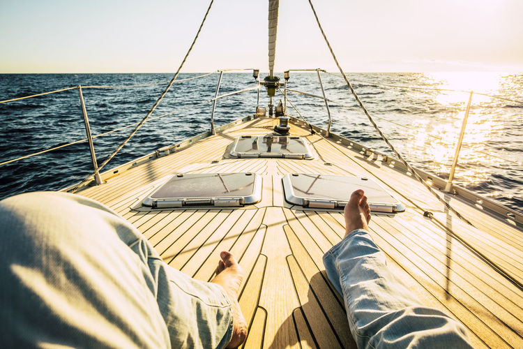 Low section of of man sitting on sailboat in sea