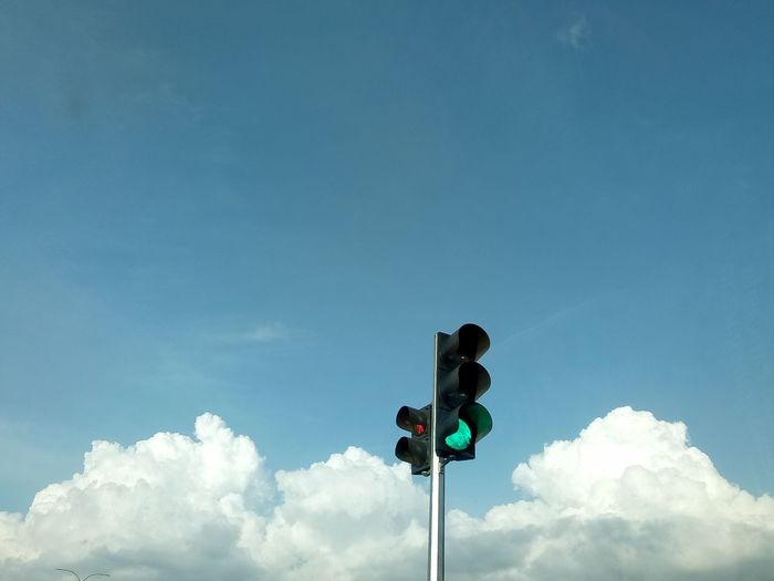 Green traffic light, clouds and blue sky.