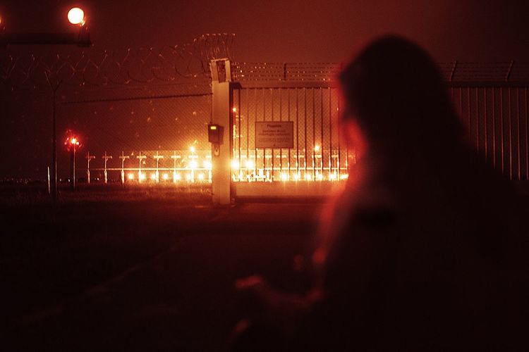 Silhouette woman standing on illuminated street at night