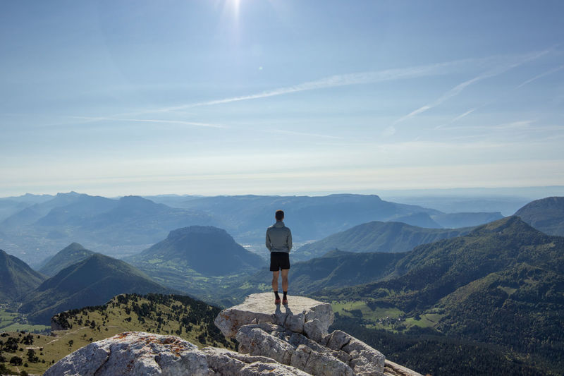 Rear view of man standing on cliff against sky
