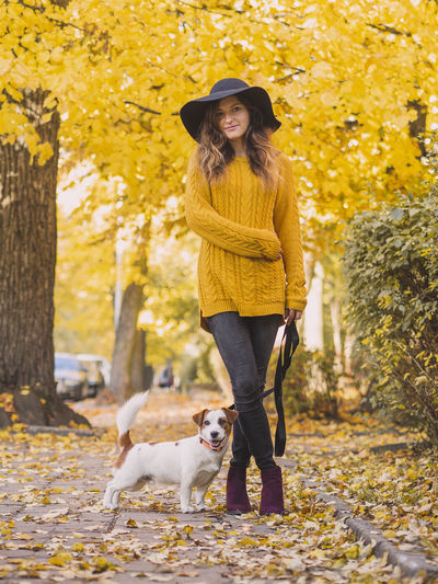 Portrait of woman with dog standing in park during autumn
