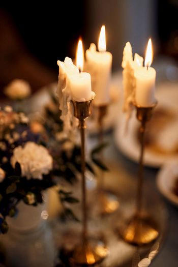 CLOSE-UP OF LIT CANDLE ON TABLE