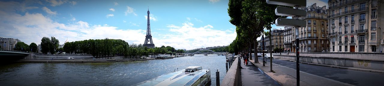 Panoramic view of cars on street by river