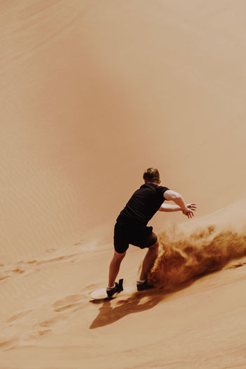 Man sandboarding in desert