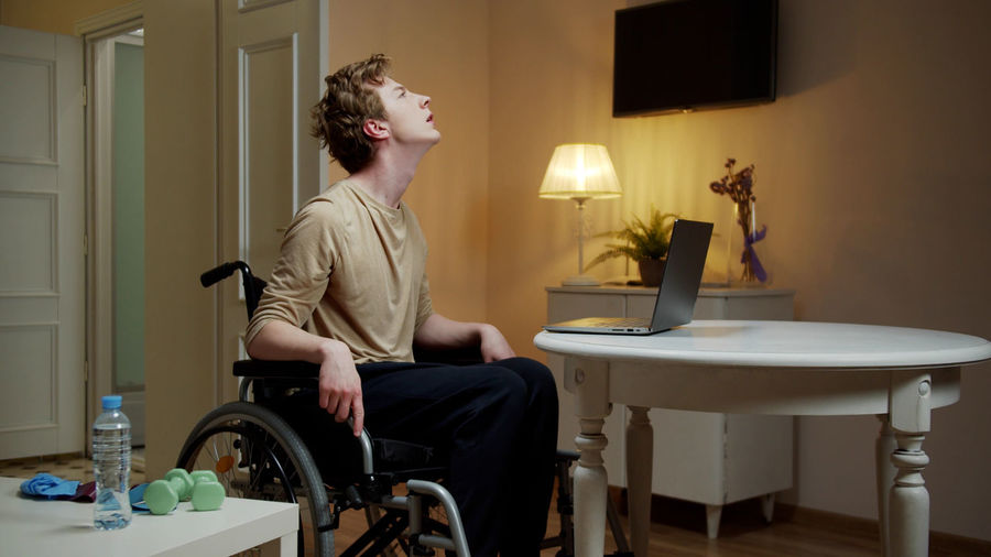 SIDE VIEW OF MAN SITTING ON TABLE