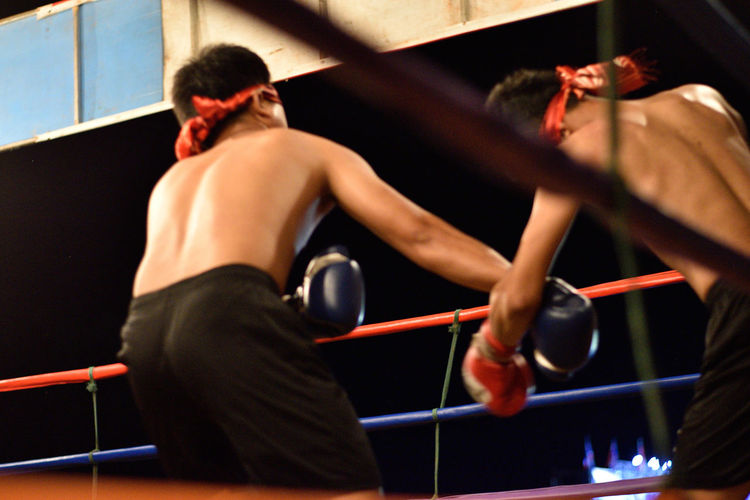 Rear view of shirtless boxers in ring