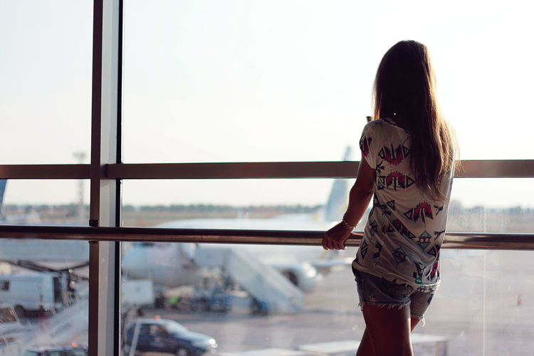 Woman looking at airplane through window