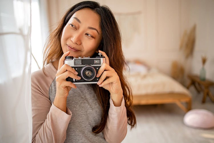 Portrait of young woman photographing with camera