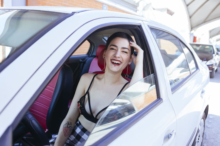 Portrait of happy young woman with short hair sitting in car