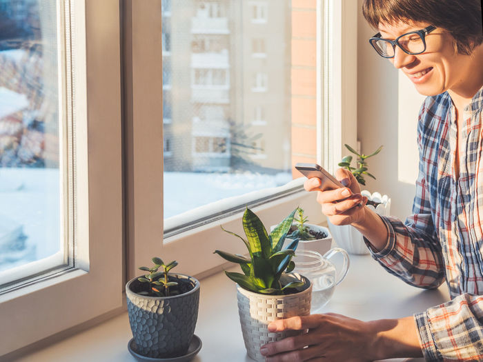 Woman takes pictures of succulent plants with smartphone. flower pots. sansevieria, crassula. 