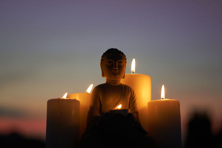 Close-up of buddha figurine with illuminated candles