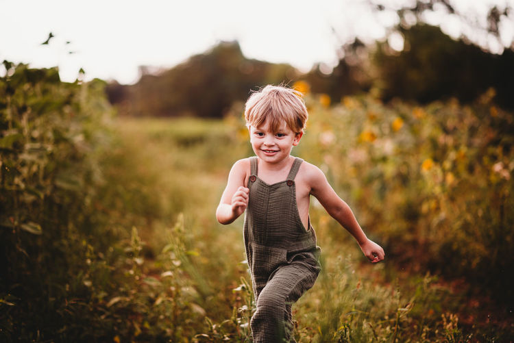 Smiling boy running in a field with sunflowers in the background