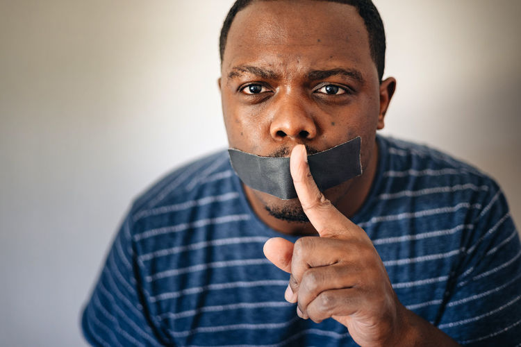 Silence or free speech concept, african american or black man with tape on mouth