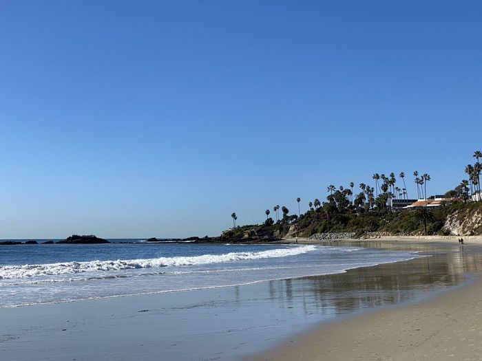 Scenic view of beach against clear blue sky