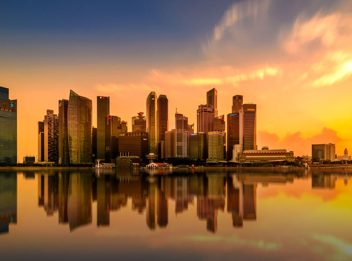 Reflection of modern buildings on marina bay during sunset