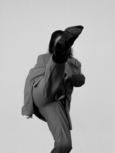 Side view of woman in suit standing against white background