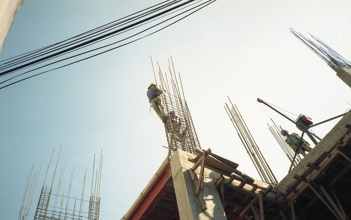 Low angle view of construction workers making reinforcing bar against clear sky