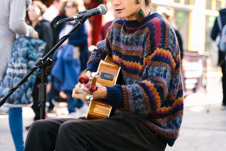 Selective focus on the lips of a young man singing while playing guitar in the street