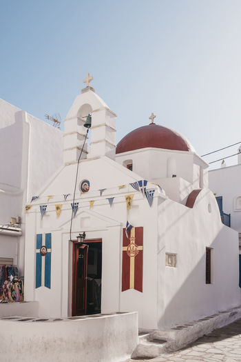 Church with a red-painted dome on a street in hora, also known as mykonos town, greece.