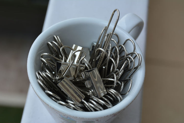 Portrait of a tiny cup filled with metal binder clips 