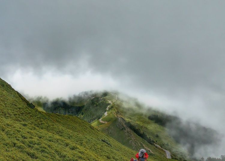 Rear view of person on hill against sky during foggy weather