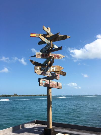 Sign post at sea against blue sky