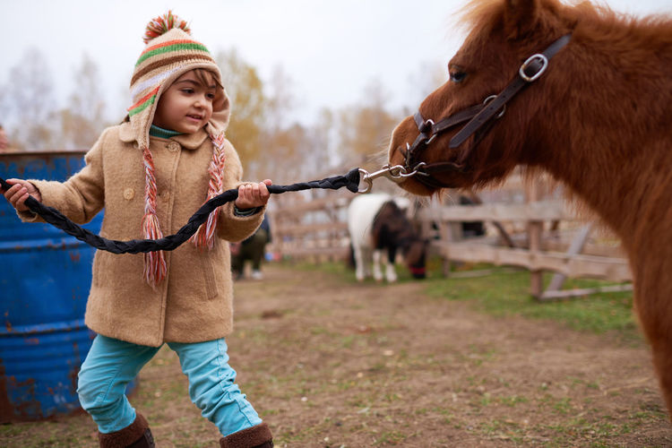 Caucasian girl leading pony by bridle