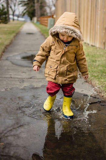 Toddler playing in puddle on sidewalk in city