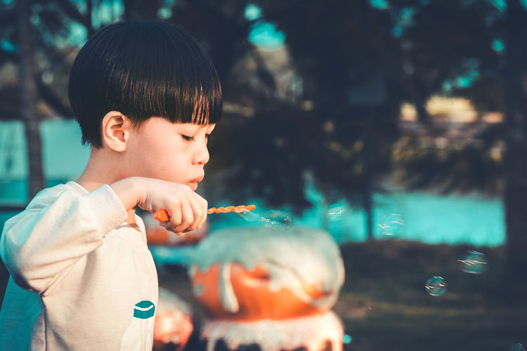 Boy blowing bubbles in park
