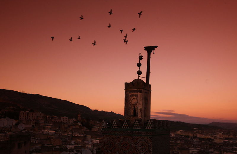Mosque and houses against orange sky