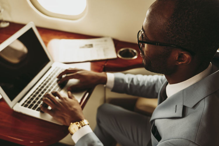 Male entrepreneur typing on laptop in airplane