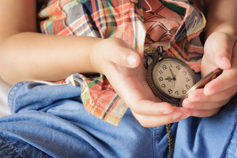Midsection of child holding pocket watch