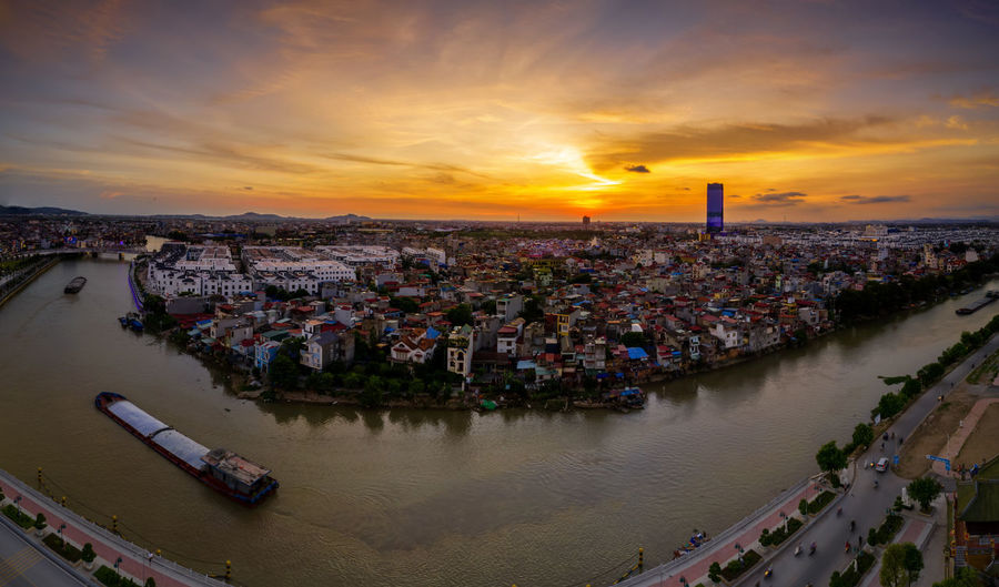 High angle view of townscape by river against sky during sunset